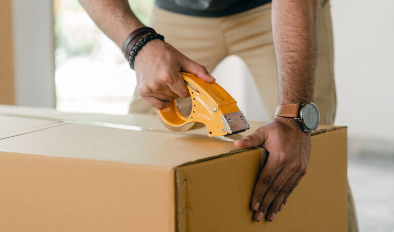 Closeup of man packing box with tape